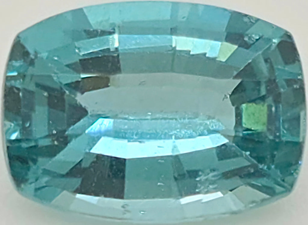 A single cushion-cut light blue gemstone with a faceted, polished finish, centered on a plain light gray background.