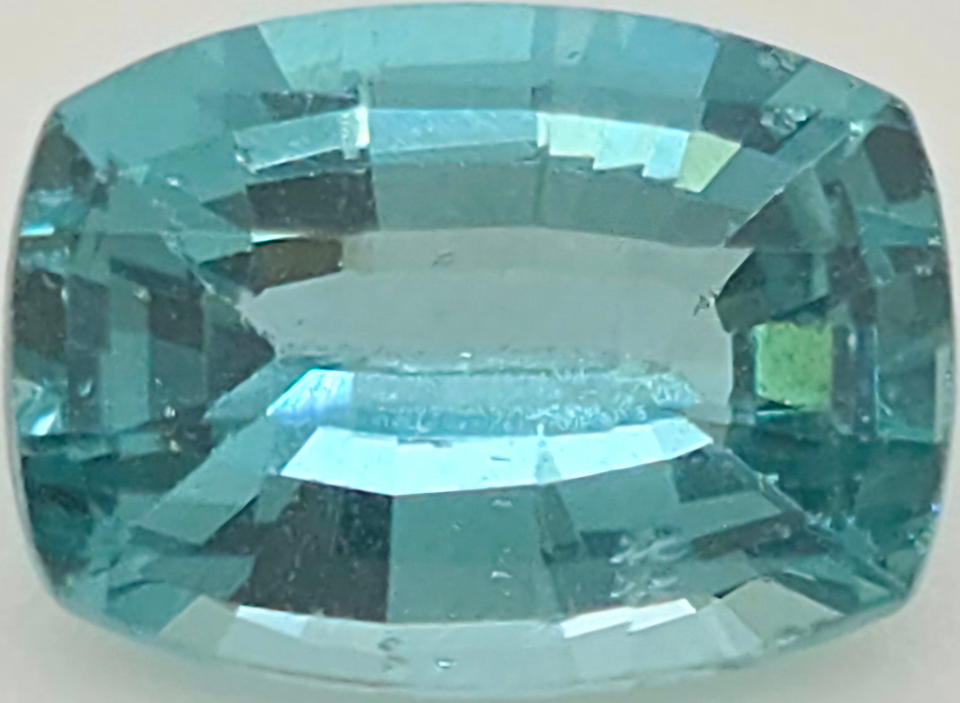 A single cushion-cut light blue gemstone with a faceted, polished finish, centered on a plain light gray background.