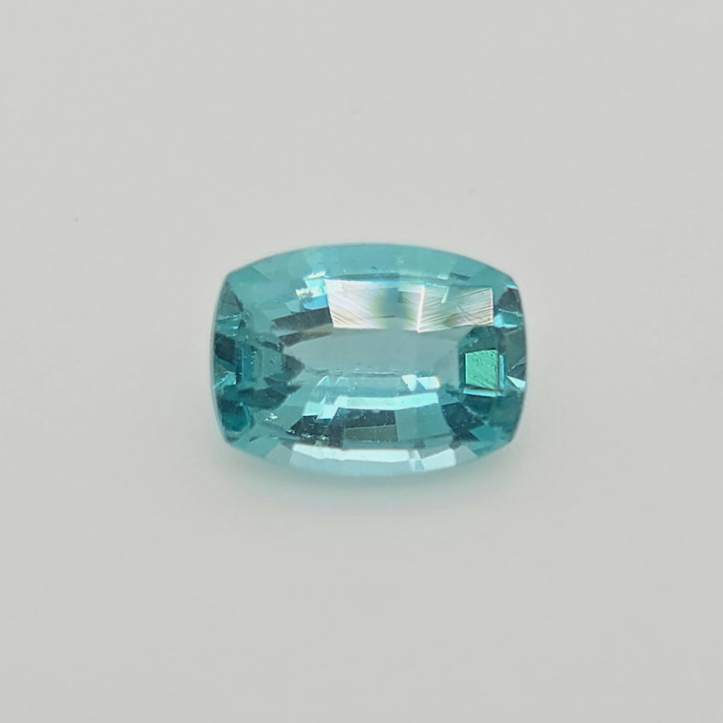 A single cushion-cut light blue gemstone with a faceted, polished finish, centered on a plain light gray background.