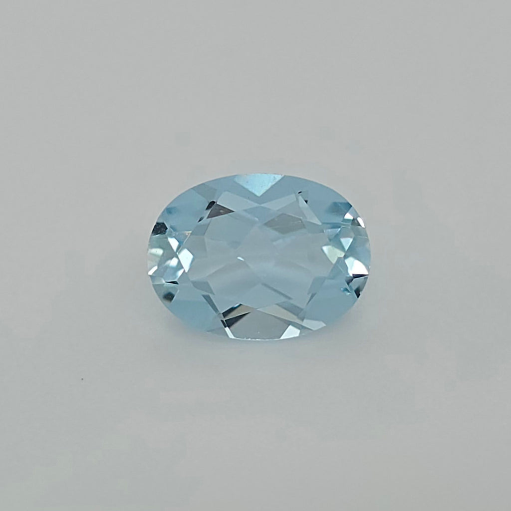 An oval-cut light blue faceted gemstone, centered on a plain light gray background.