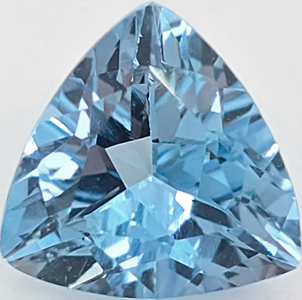 A triangular, faceted light blue gemstone, shown in sharp detail against a plain white background.