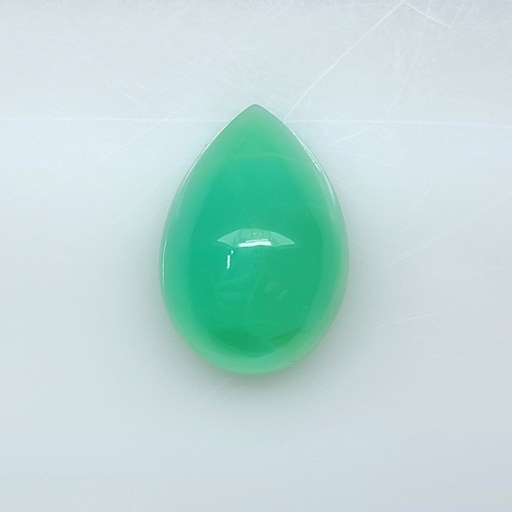 A teardrop-shaped green gemstone cabochon with a smooth, polished surface, displayed on a light gray background.
