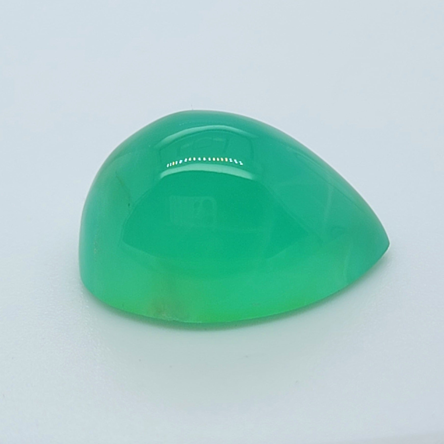 A polished green cabochon gemstone with a teardrop shape, displayed on a clean white background.