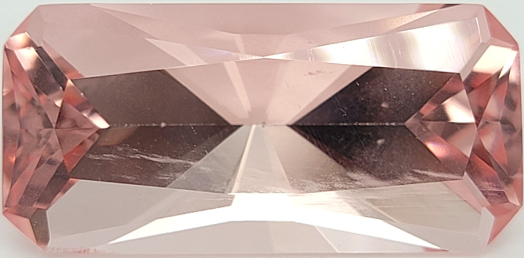 A rectangular pink gemstone with a faceted, brilliant cut, shown against a white background.