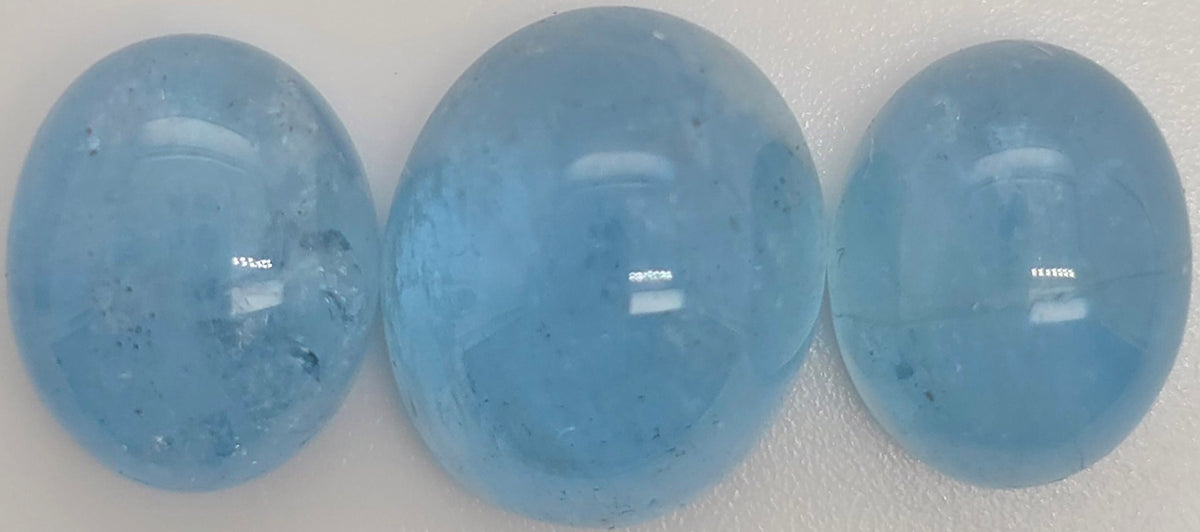 Three smooth, polished oval blue gemstones arranged side by side on a plain light background.