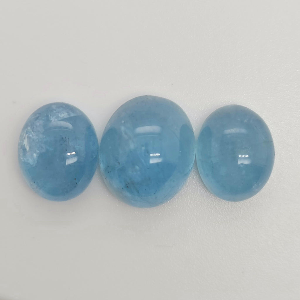 Three oval blue gemstone cabochons side by side on a white background