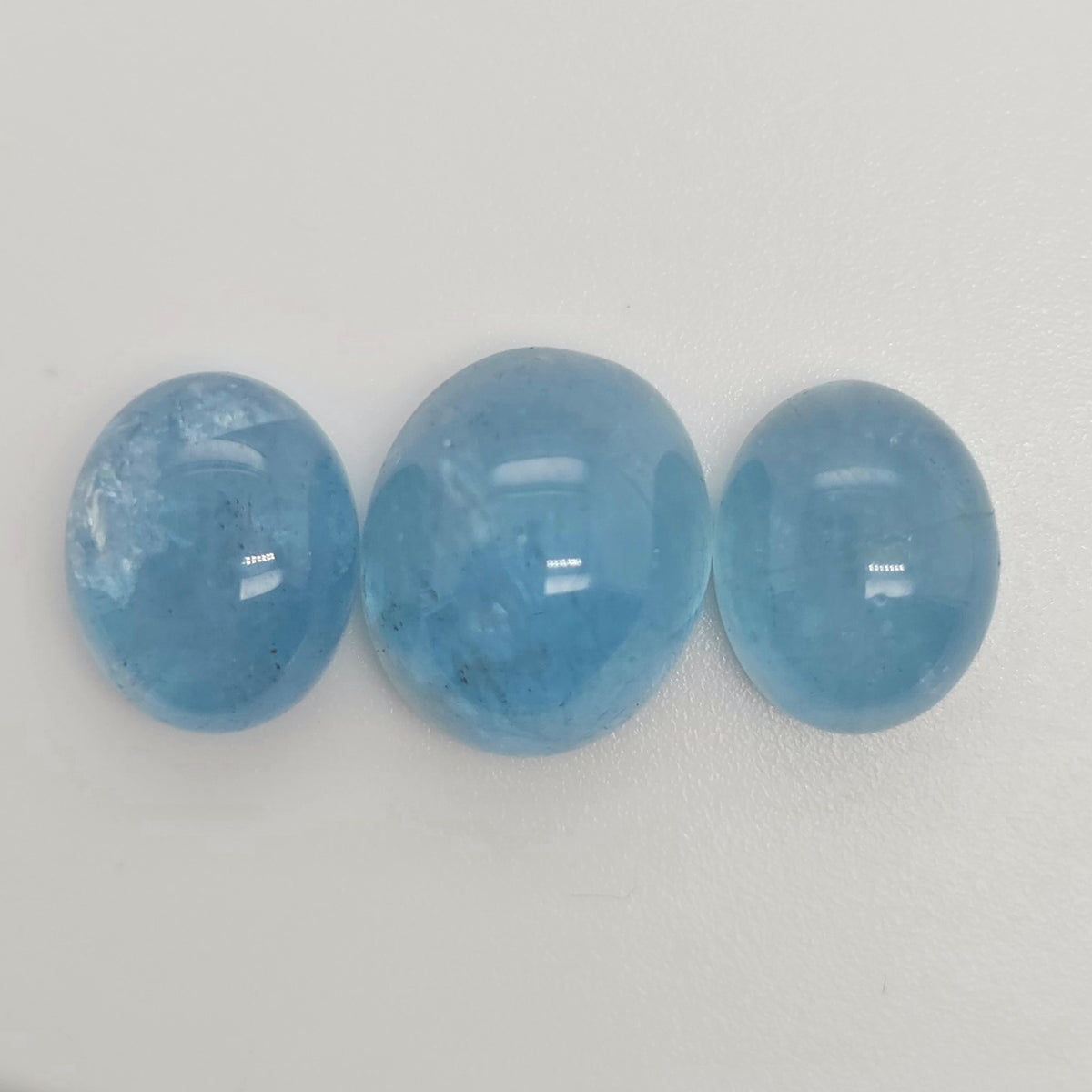 Three oval blue gemstone cabochons side by side on a white background