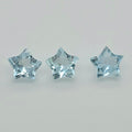 Three faceted star-shaped light blue gemstones arranged horizontally on a plain light gray background.