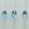 Three oval-cut light blue gemstones arranged horizontally against a plain white background.