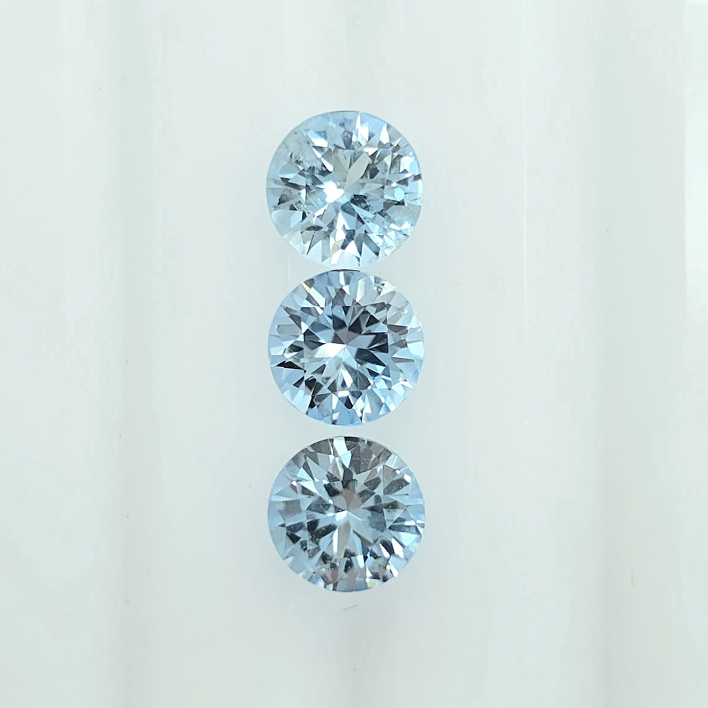 Three round brilliant-cut light blue gemstones arranged vertically on a plain white background.