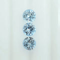 Three round brilliant-cut light blue gemstones arranged vertically on a plain white background.