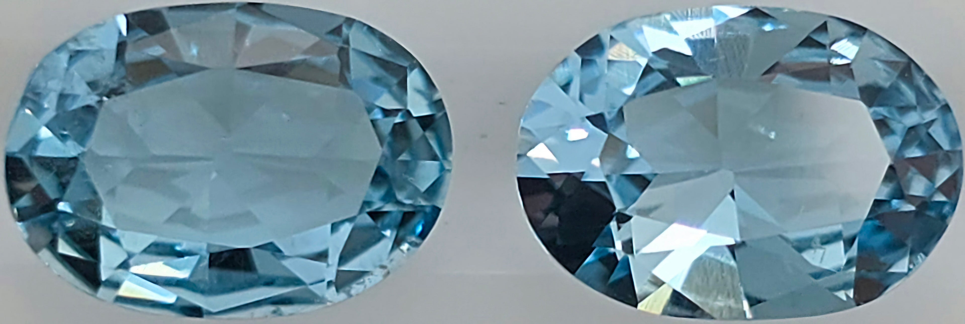 Two oval-cut light blue gemstones shown side by side on a plain light background.