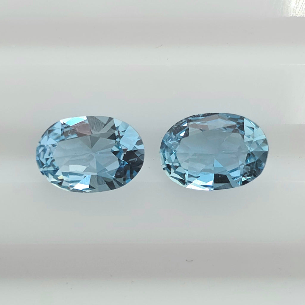 Two oval-cut light blue gemstones displayed side by side on a plain white background.