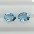 Two oval-cut light blue gemstones displayed side by side on a plain white background.
