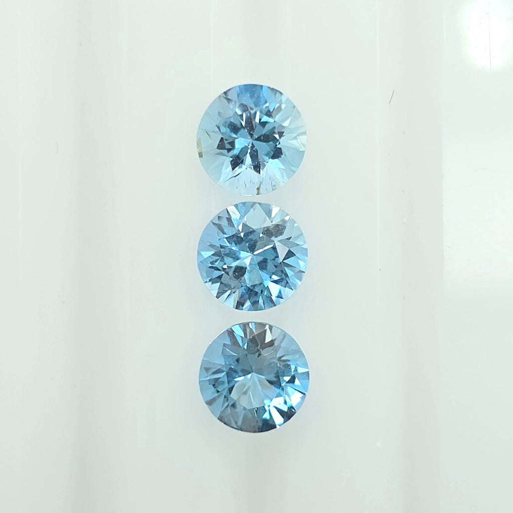 Three round-cut light blue gemstones arranged vertically on a plain white background.