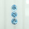 Three round-cut light blue gemstones arranged vertically on a plain white background.