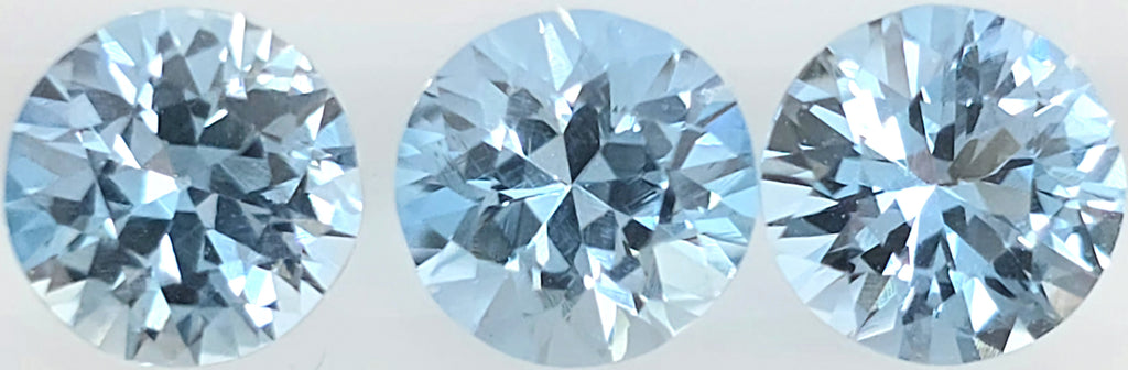 Three round brilliant-cut light blue gemstones shown side by side on a plain white background.