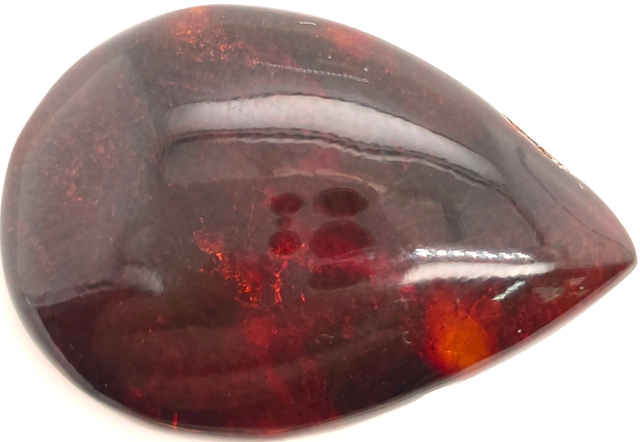 A polished teardrop-shaped dark brownish orange gemstone with natural inclusions and a glossy finish, shown on a plain white background.