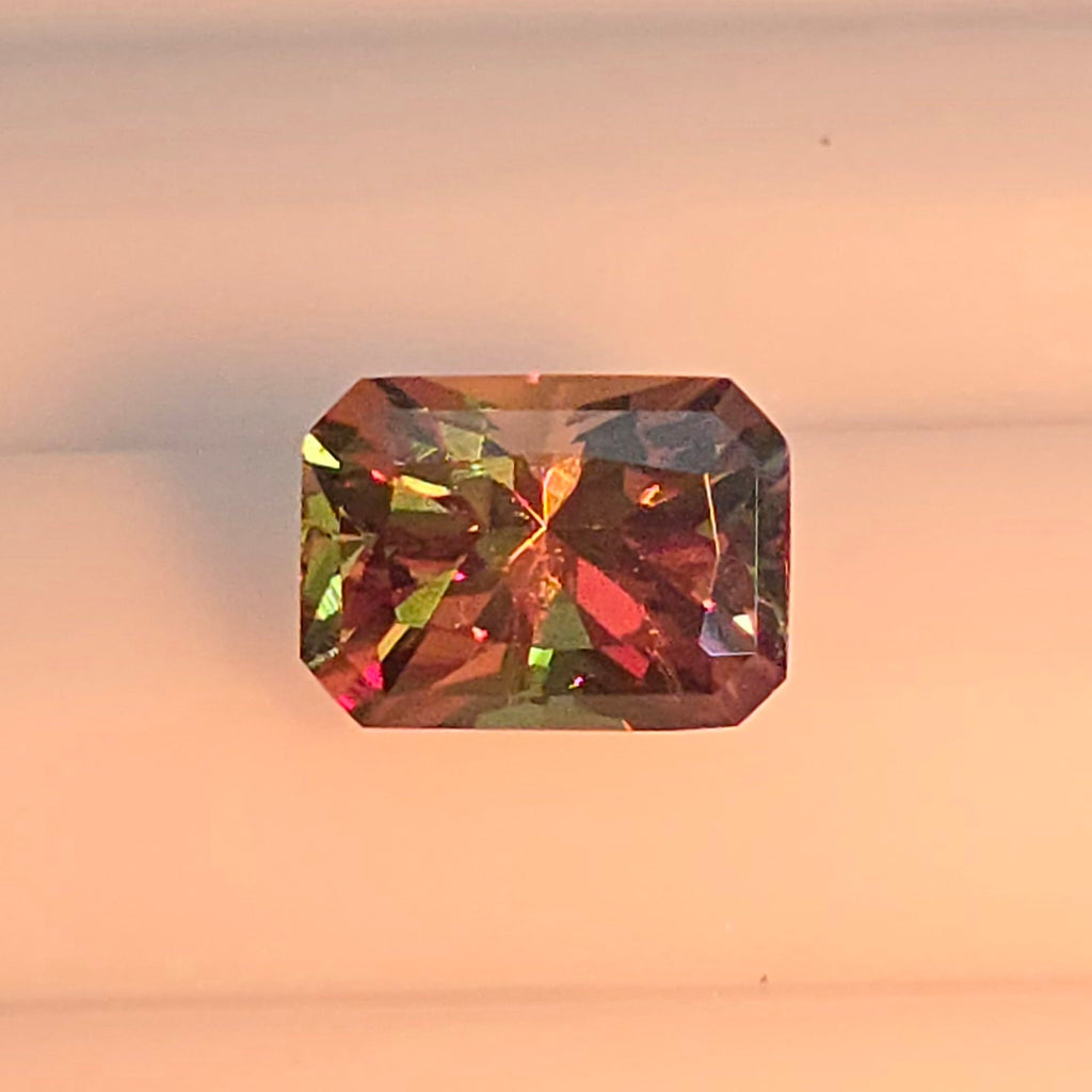 Multicolored gemstone on a light pink background