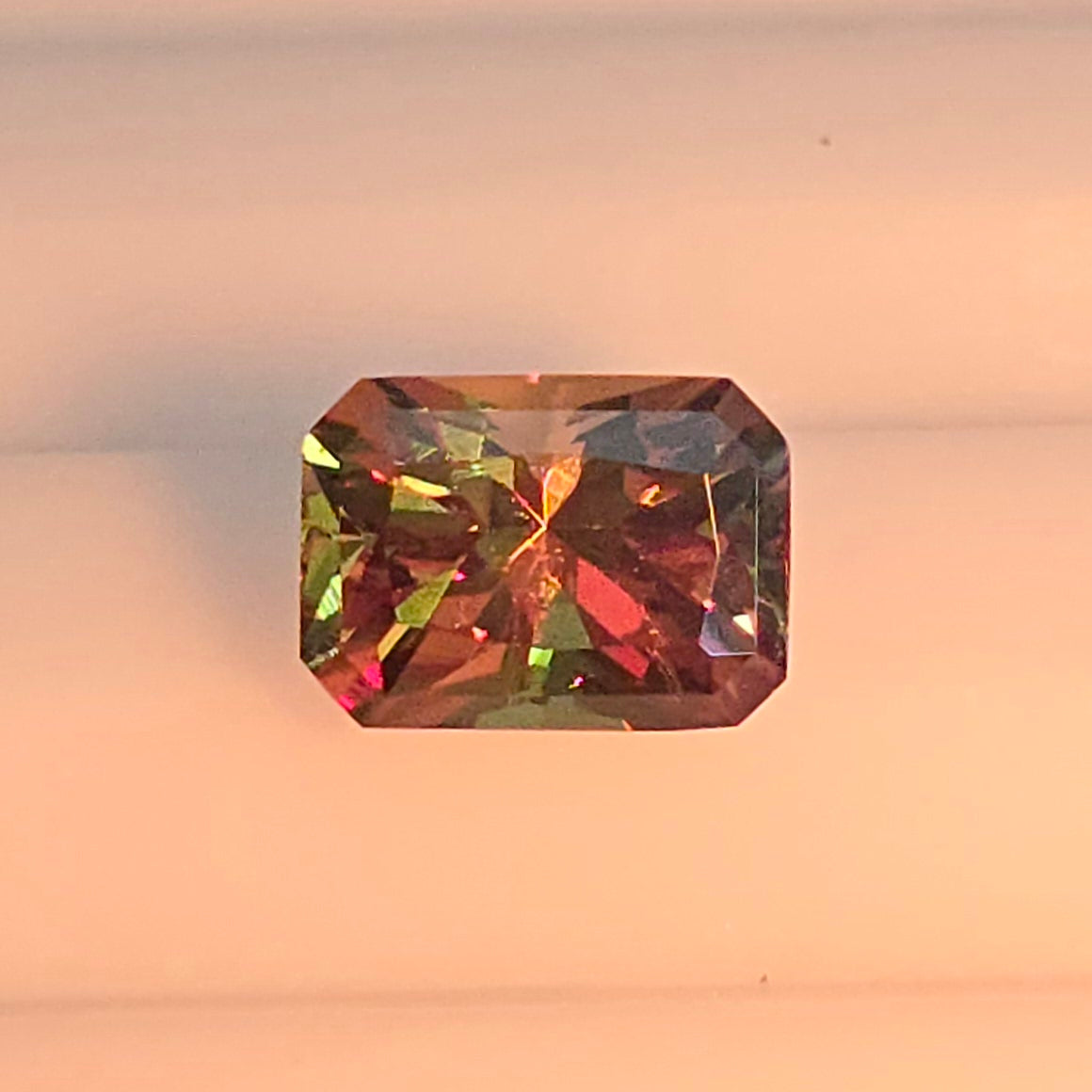 Multicolored gemstone on a light pink background