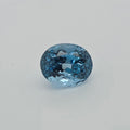 An oval-cut light blue gemstone with a faceted, sparkling surface, centered on a plain light gray background.