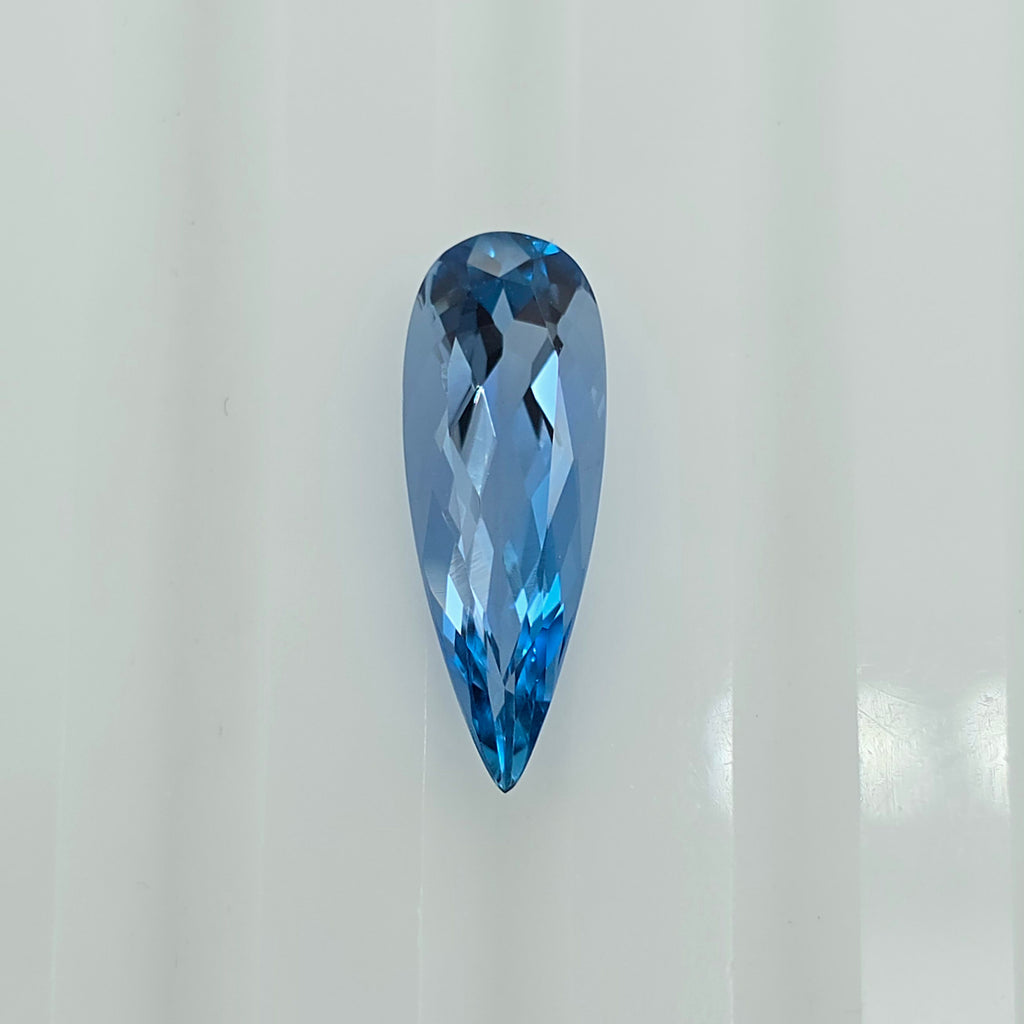 A faceted pear-shaped blue gemstone, centered on a clean white background.