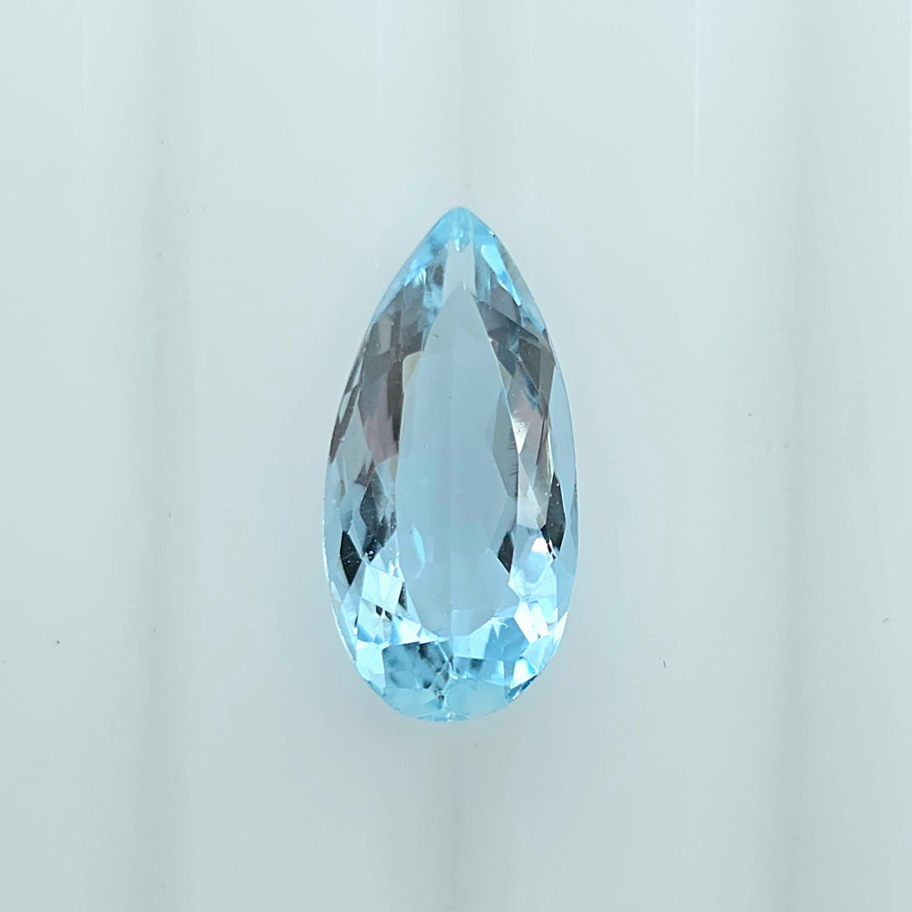 A single faceted teardrop-shaped light blue gemstone, centered on a clean white background.