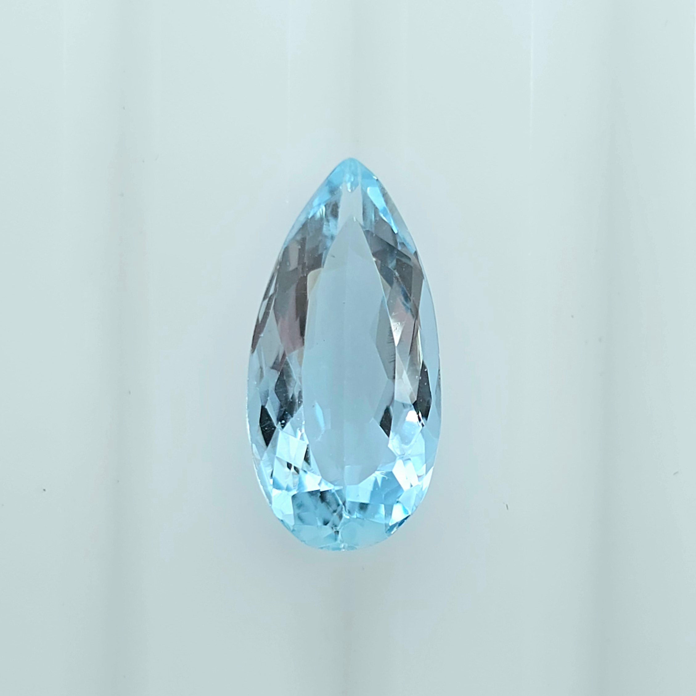 A single faceted teardrop-shaped light blue gemstone, centered on a clean white background.
