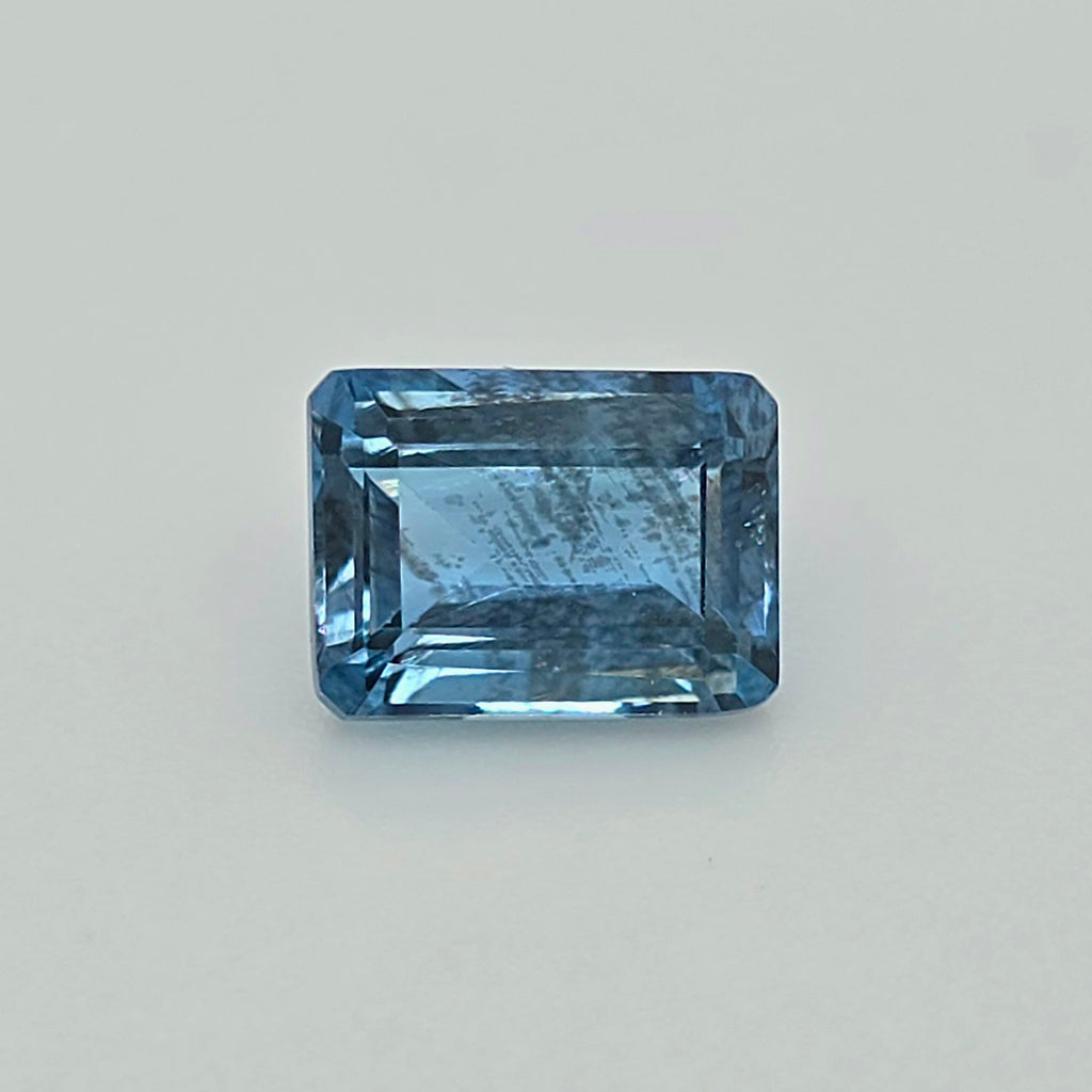 A rectangular blue gemstone with a beveled edge, shown on a plain light gray background.