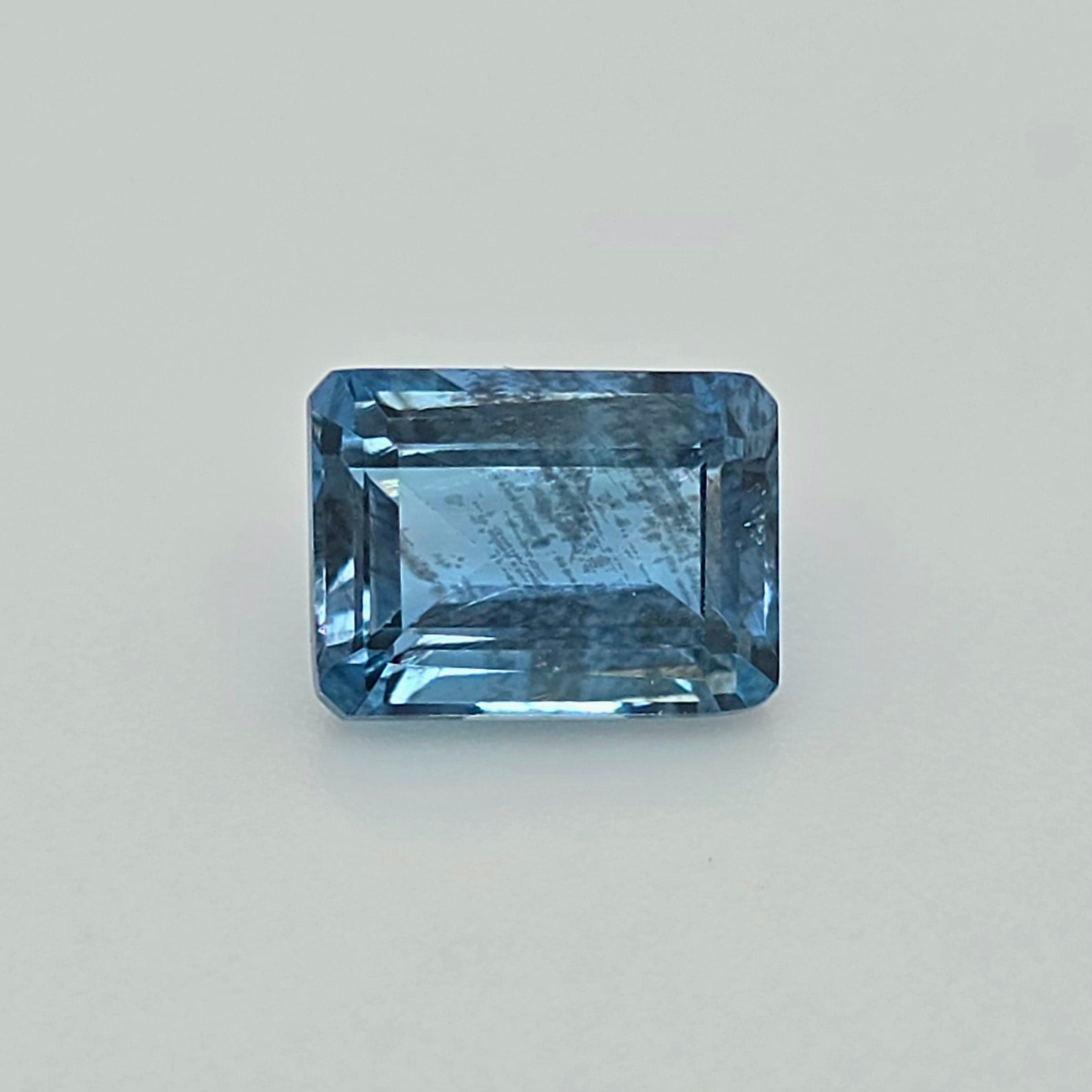 A rectangular blue gemstone with a beveled edge, shown on a plain light gray background.