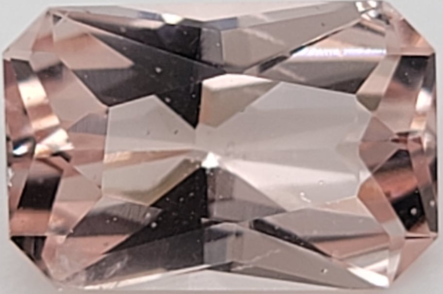 A faceted rectangular pink gemstone, likely a morganite, shown in a close-up studio shot against a white background.