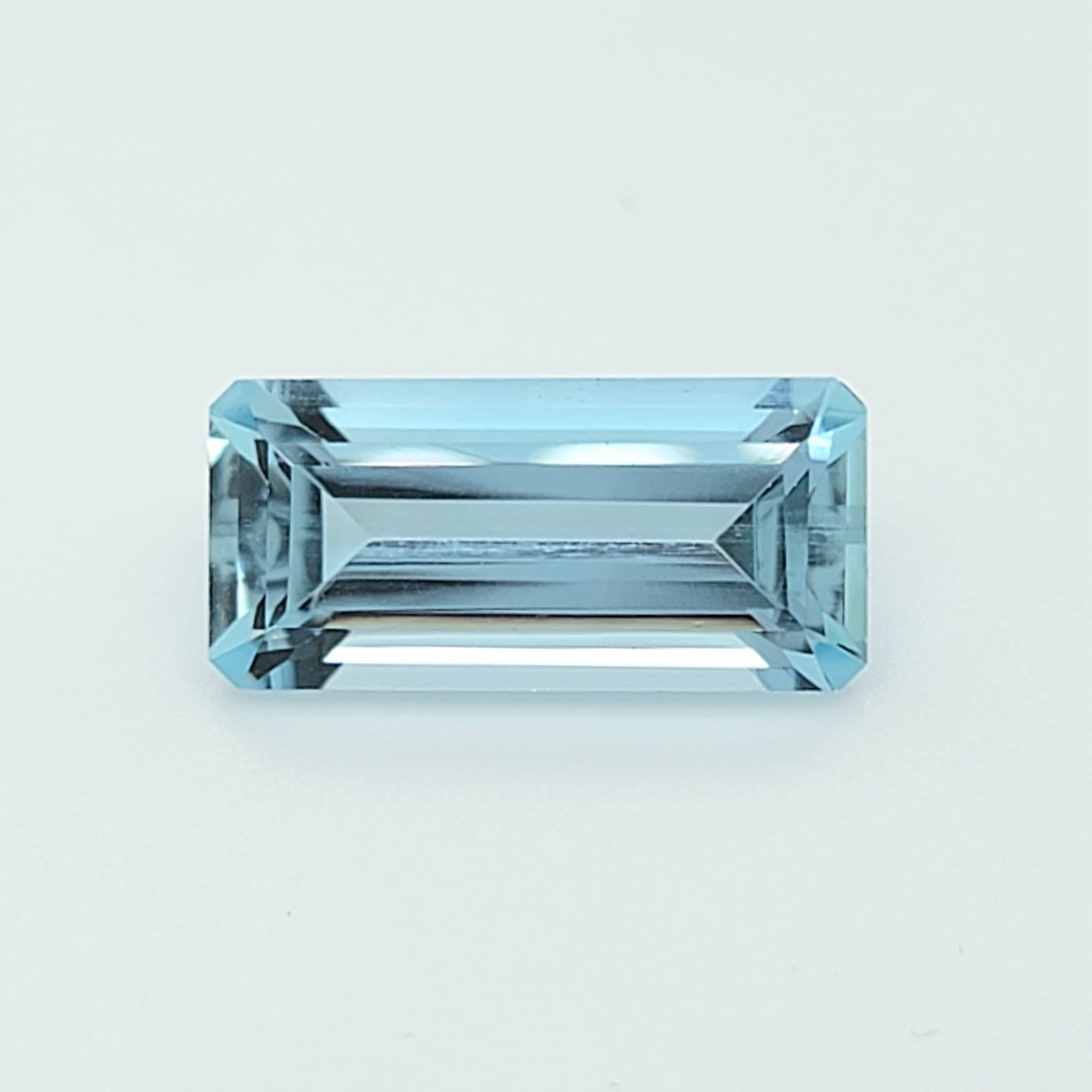 A rectangular emerald-cut light blue gemstone with a brilliant faceted finish, displayed on a clean white background.