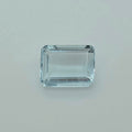 A rectangular emerald-cut gemstone with a light blue tint, photographed on a plain light gray background.
