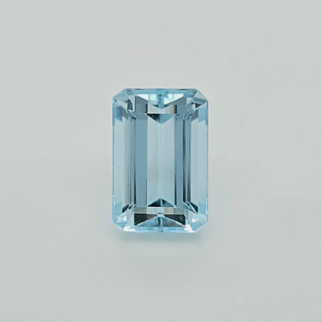 A single light blue emerald-cut gemstone centered on a plain light gray background.