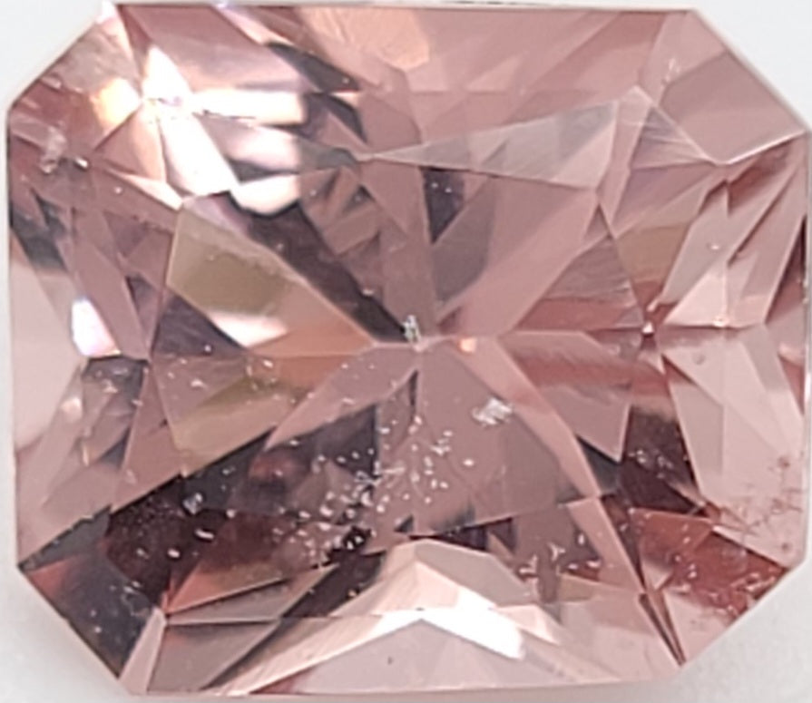 A faceted radiant cut pink gemstone, shown in close-up against a white background.