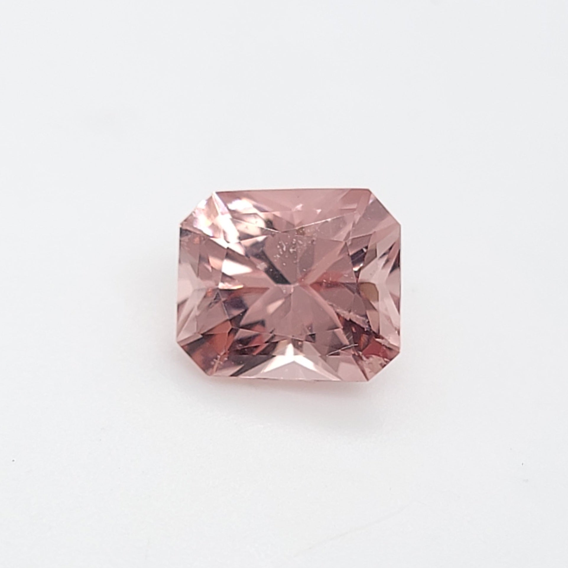 A single rectangular radiant cut pink gemstone with faceted edges, centered on a plain white background.