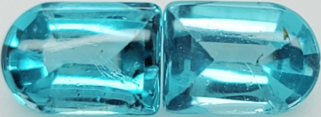 A pair of light blue faceted gemstone cabochons with a rounded top and rectangular body, displayed side-by-side on a plain light background.