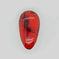 A polished teardrop-shaped reddish orange gemstone with dark inclusions and speckles, displayed on a light gray background.