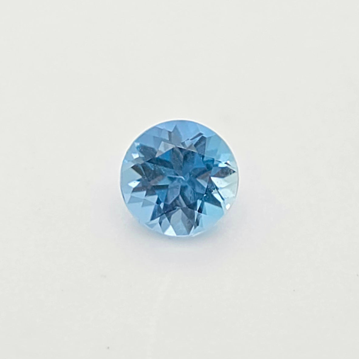A single round-cut blue gem centered on a plain white background.