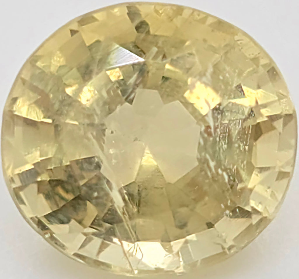 An oval faceted yellow gemstone, likely a shown in a top-down view against a plain white background.