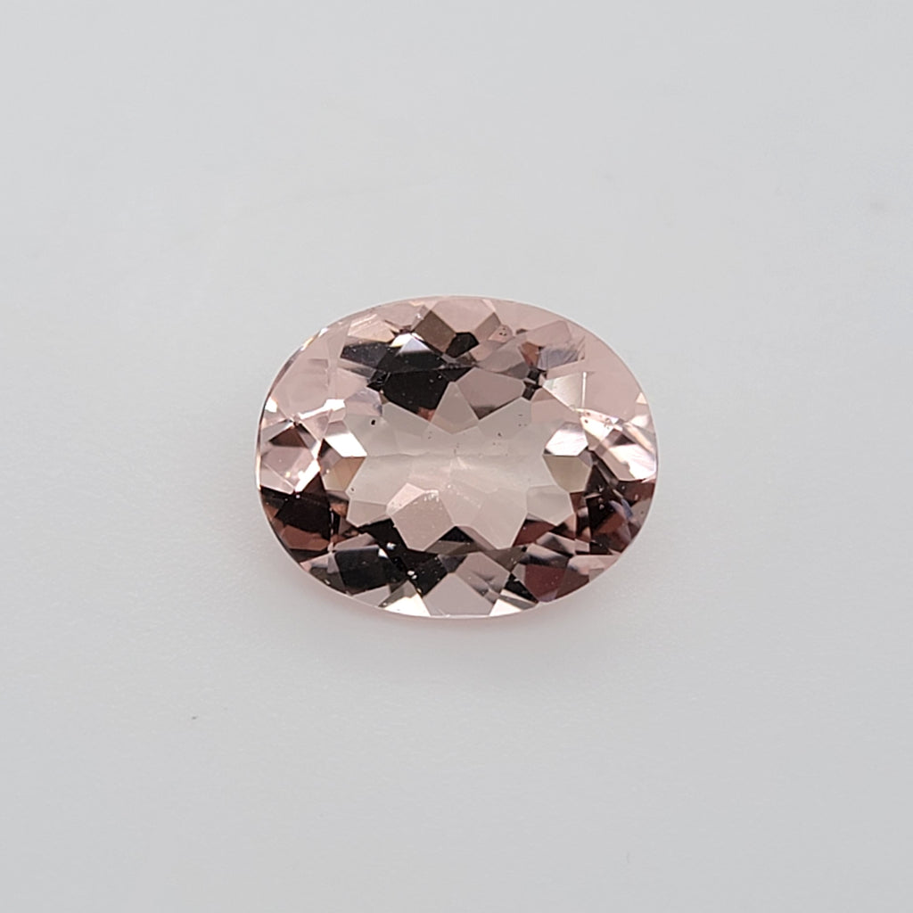 Transparent oval pink gemstone on a white background