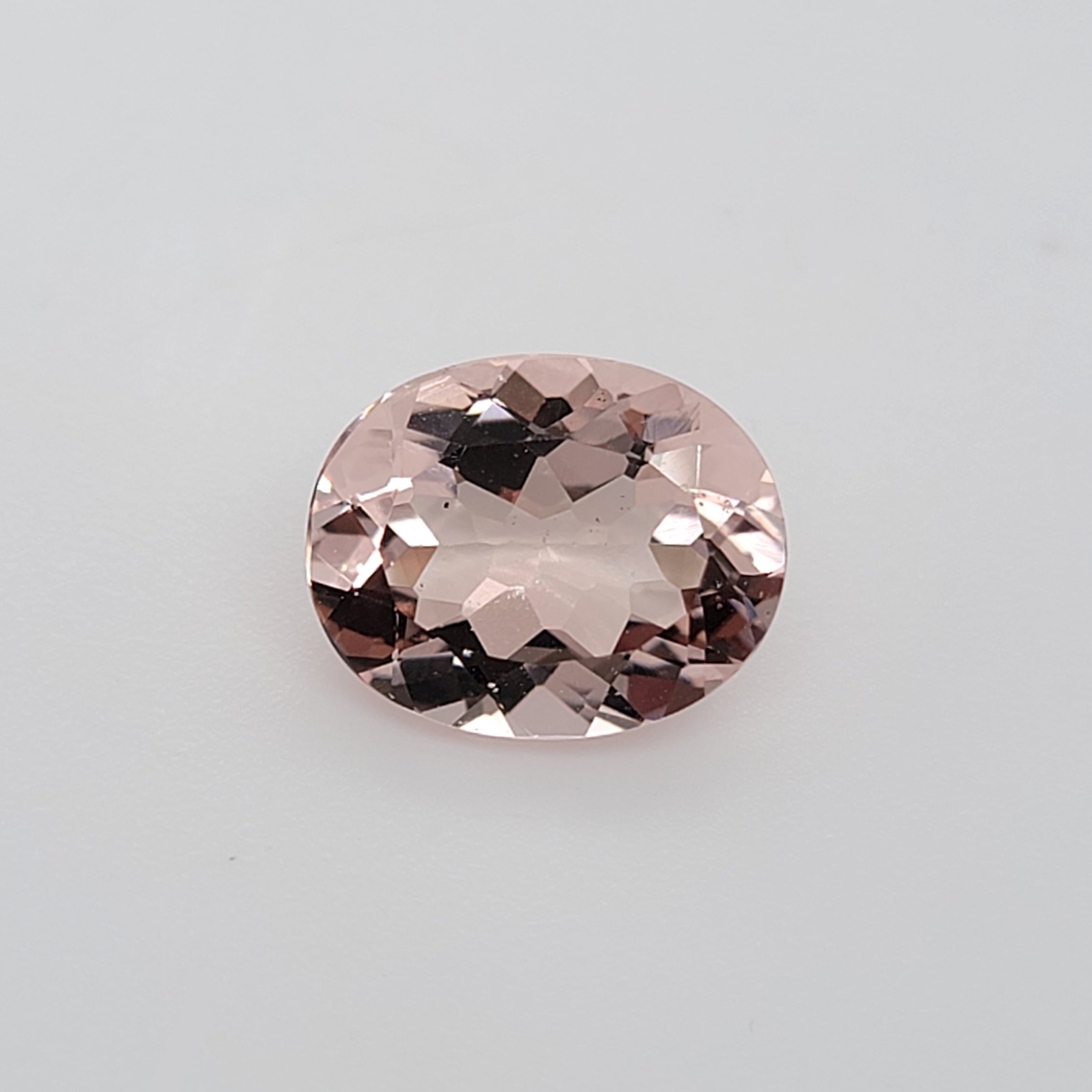 Transparent oval pink gemstone on a white background