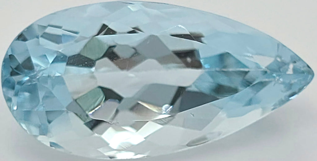 A faceted pear-cut light blue gemstone, shown on a plain light gray background.