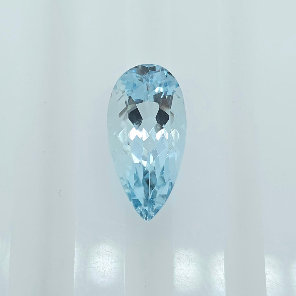 A single faceted pear-shaped light blue gemstone centered against a bright white background.