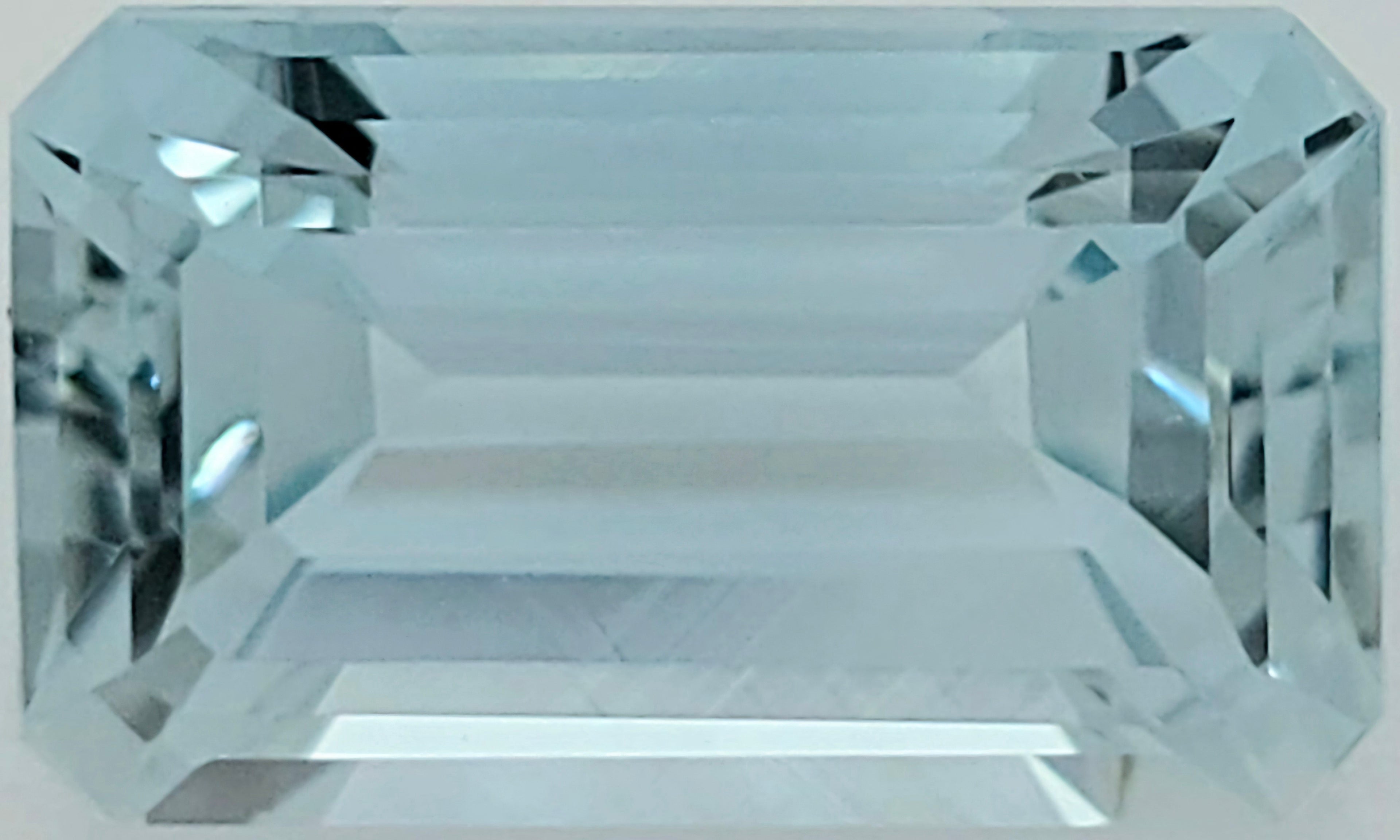 A rectangular emerald-cut light blue gemstone with a faceted, reflective surface, shown against a plain white background.