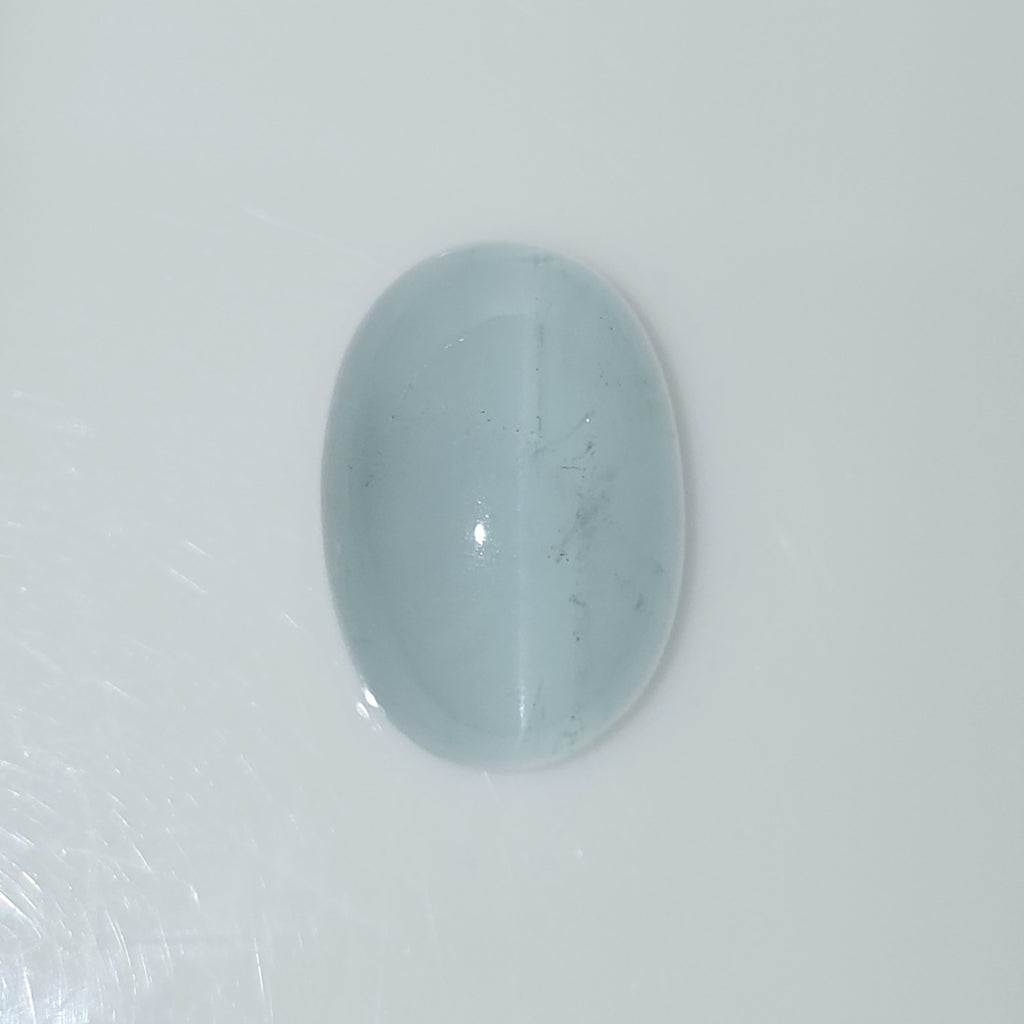 Oval domed light blue gemstone cabochon on a white background