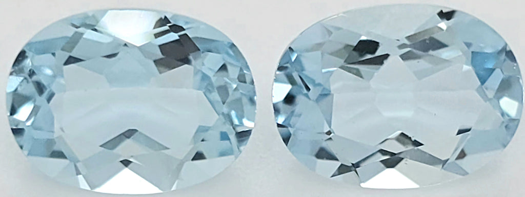 Two oval-cut light blue gemstones shown side by side on a plain white background.