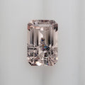 An emerald-cut pink gemstone with iridescent inclusion on a clean white background.