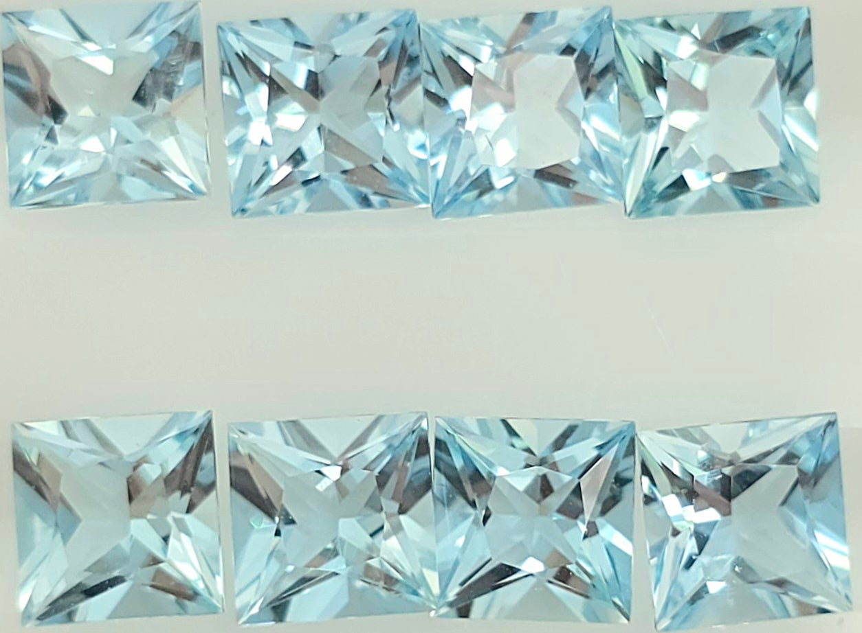 Eight light blue square faceted gemstones arranged in two rows on a plain white background.