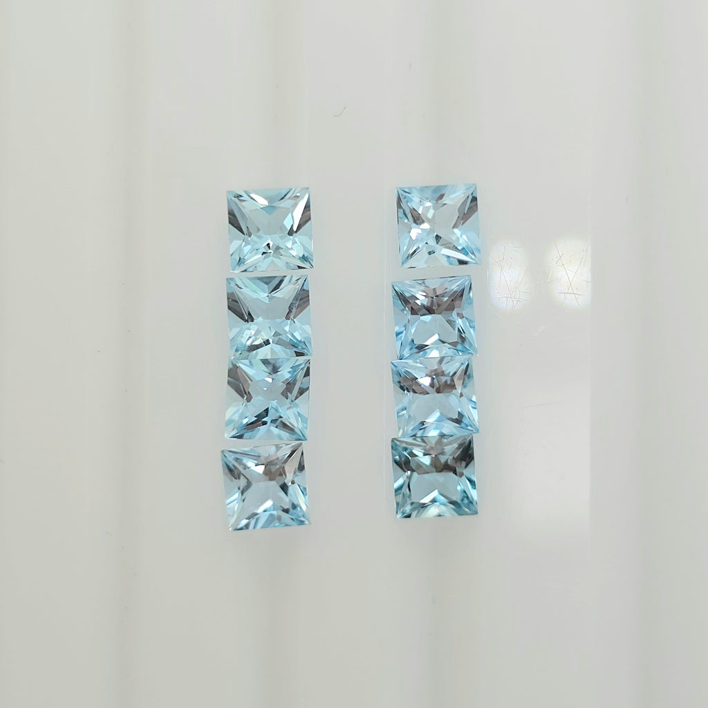 Eight square faceted light blue gemstones arranged in two vertical columns against a plain white background